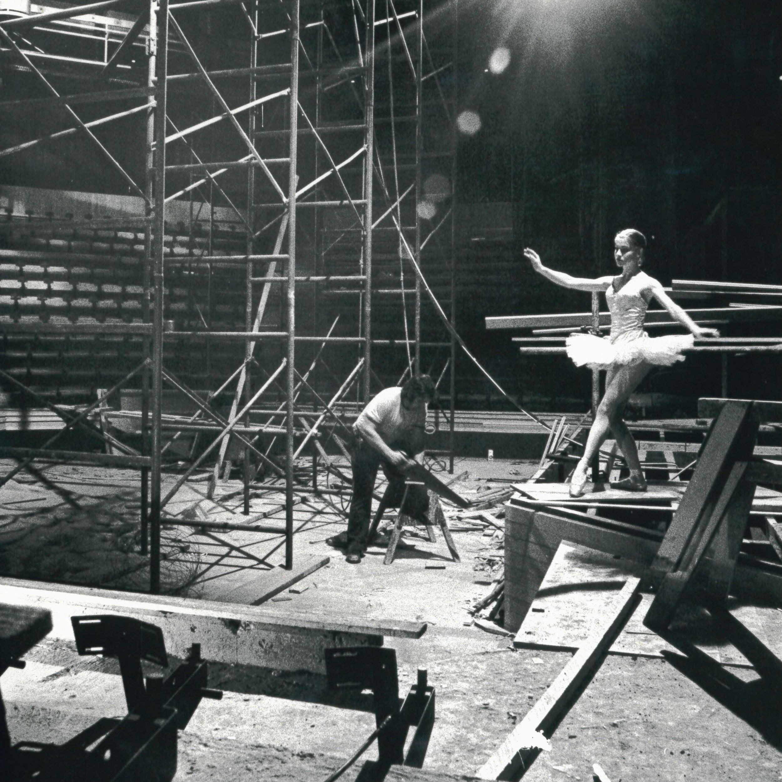 Black and white archival image of the construction of the York Theatre with a ballerina perched on building materials. 