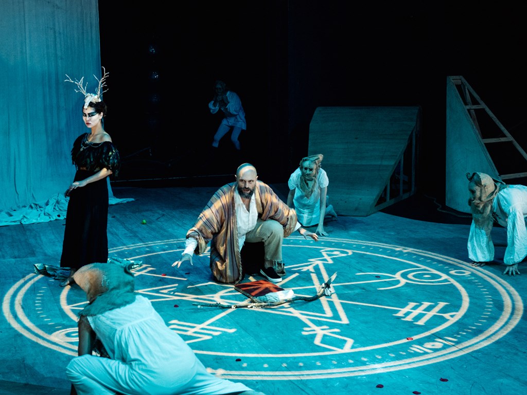 Promotional image of The Tempest/Hag-Seed Symposium for Seymour Centres Arts Education Program depicting a group of players gathered around a symbol projected onto the floor.