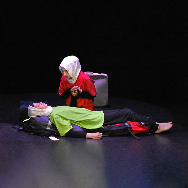 Promotional image of Refugee Diaries for Seymour Centres Arts Education Program depicting a girl lying down on a backpack with another girl crouched over her body holding her hand.